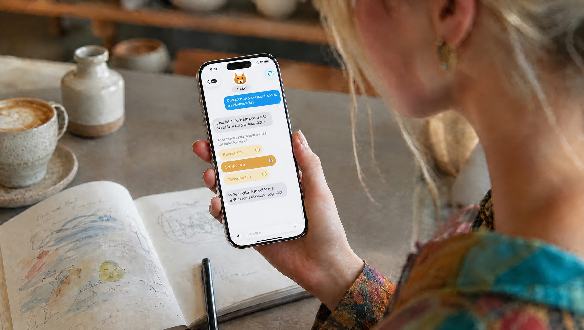 À une table de café, une personne lit sur son téléphone sa conversation avec Turbo : le lien reçu pour le 888, rue de la Montagne, un sondage pour l'heure de la visite, et la visite inscrite.